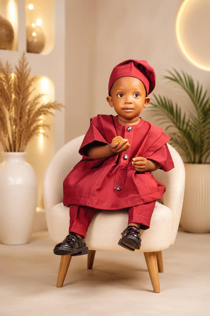 Toddler boy in a maroon traditional agbada and cap