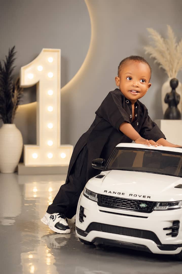 Toddler boy beside a toy Range Rover with a light-up number one, first birthday shoot