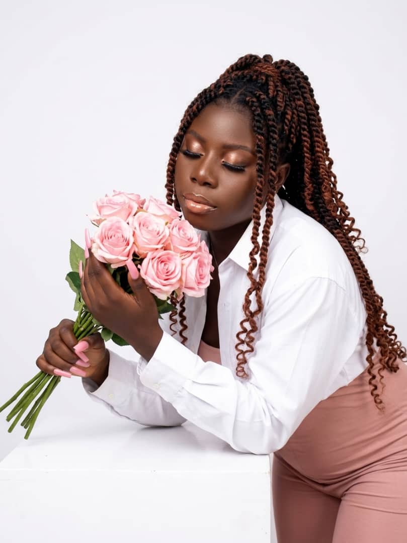 Woman in a white shirt leaning over a bouquet of pink roses