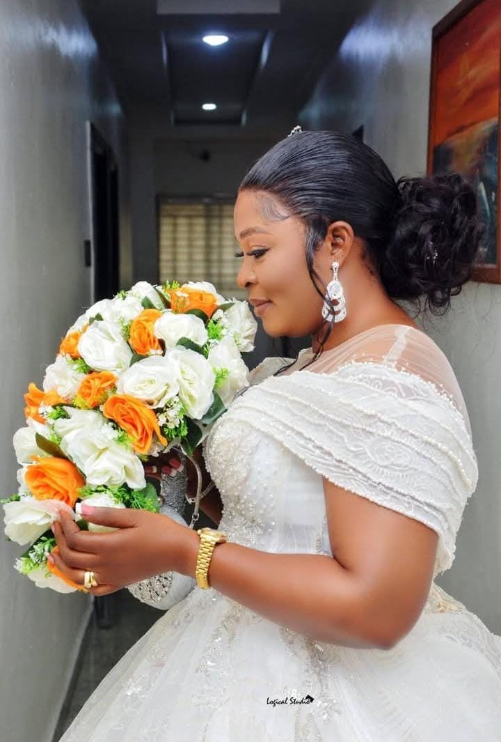 Bride in profile holding an orange and white bouquet