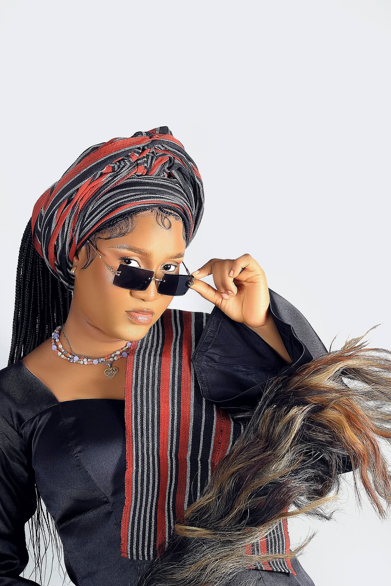 Woman in a striped headwrap and rimless sunglasses draped in a two-tone fur stole