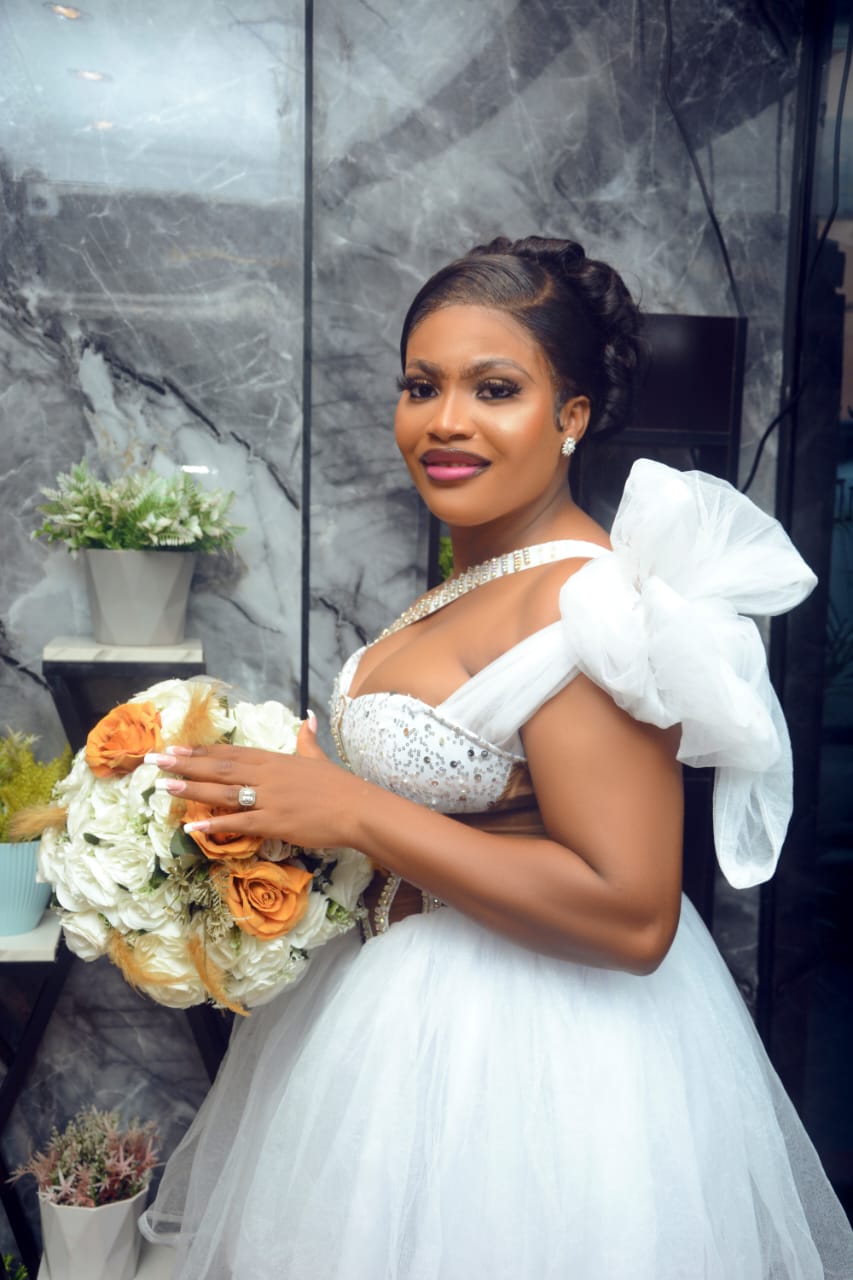 Bride in a white ballgown with a bow shoulder detail holding a bouquet
