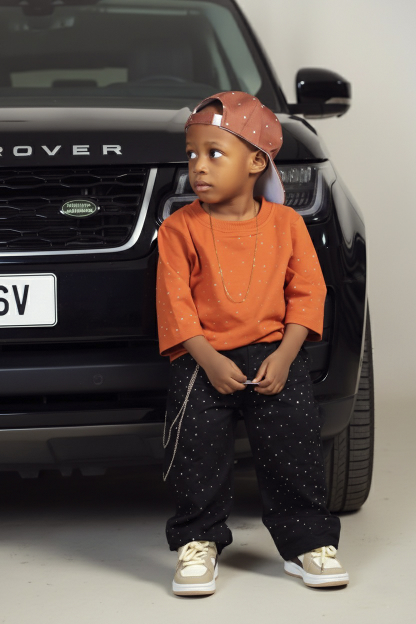 Toddler boy in an orange top and backwards cap leaning on a Range Rover