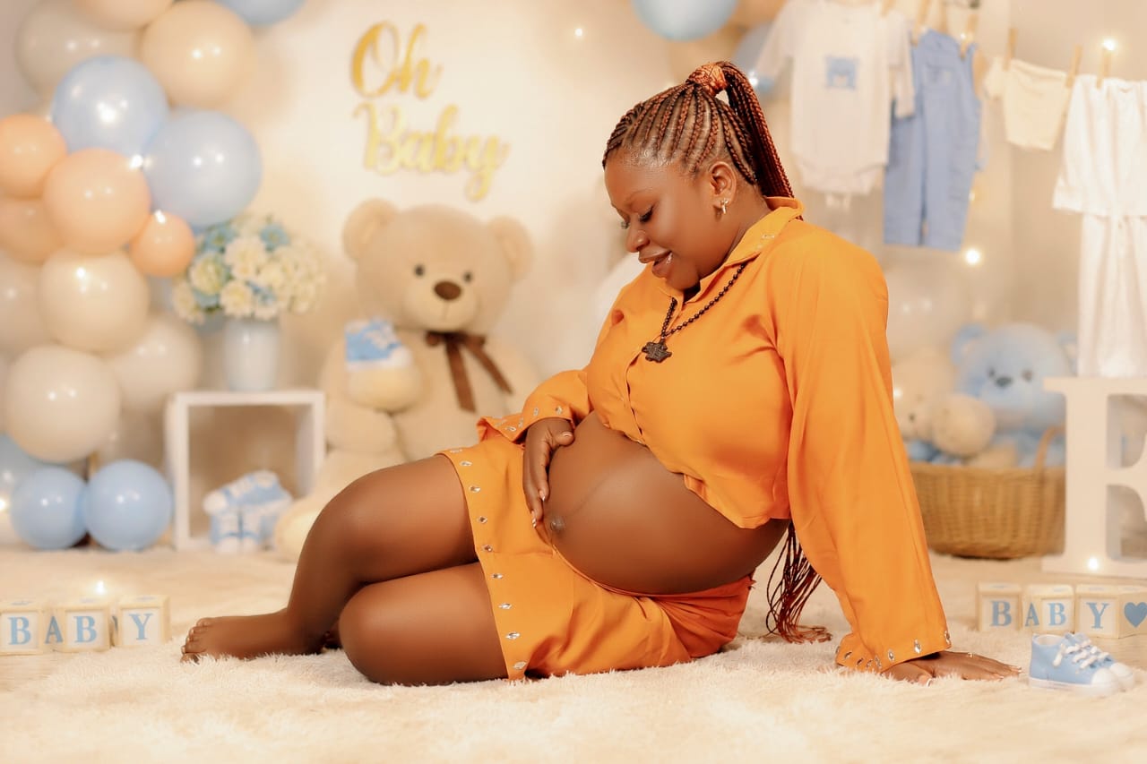 Pregnant woman in an orange outfit posing at an Oh Baby maternity-themed shoot